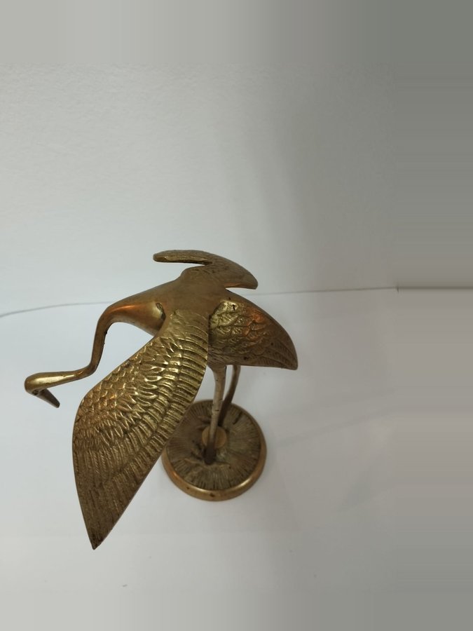 Brass heron with wings spread on a sunburst base